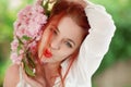 Beautiful young woman with red hair having fun standing in the garden with cherry blossom branch Royalty Free Stock Photo