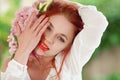 Beautiful young woman with red hair having fun standing in the garden with cherry blossom branch Royalty Free Stock Photo