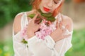 Beautiful young woman with red hair having fun standing in the garden with cherry blossom branch Royalty Free Stock Photo