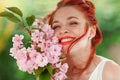 Beautiful young woman with red hair having fun standing in the garden with cherry blossom branch Royalty Free Stock Photo