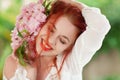 Beautiful young woman with red hair having fun standing in the garden with cherry blossom branch Royalty Free Stock Photo