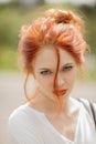 Beautiful young woman with red hair, outside in a park in the sunlight, looking into the camera Royalty Free Stock Photo