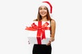 Beautiful young woman in a red Santa Claus hat and in a black elegant dress, with a gift on a white background, holiday concept, Royalty Free Stock Photo