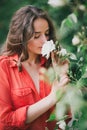 Beautiful young woman in a red shirt smelling a rose Royalty Free Stock Photo