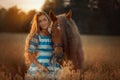 Beautiful young woman with red tinker horse in oats field