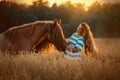 Beautiful young woman with red tinker horse in oats field