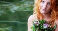 Beautiful young woman, redhead bride, with red hair, sits eagerly abandoned with a bouquet of flowers in a boat and waits full of Royalty Free Stock Photo