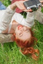 Beautiful young woman relaxing with camera in her hand on garden bench in green grass Royalty Free Stock Photo