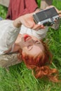 Beautiful young woman relaxing with camera in her hand on garden bench in green grass Royalty Free Stock Photo