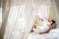 Beautiful young woman relaxing, laying on bed with canopy and beauty mask on her face Royalty Free Stock Photo