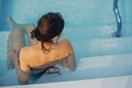 Beautiful young  woman relaxing in pool, enjoying summer holiday, back view. Brunette girl on summer vacation in luxury resort, Royalty Free Stock Photo