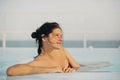 Beautiful young woman relaxing in pool, enjoying warm sunlight and wind. Brunette girl on summer vacation in luxury resort, Royalty Free Stock Photo