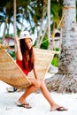 Beautiful young woman relaxing on rattan hammock on the white sand beach during travel vacation Royalty Free Stock Photo