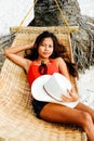 Beautiful young woman relaxing on rattan hammock on the white sand beach during travel vacation Royalty Free Stock Photo