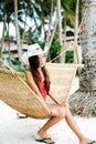 Beautiful young woman relaxing on rattan hammock on the white sand beach during travel vacation Royalty Free Stock Photo