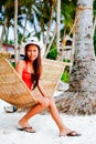 Beautiful young woman relaxing on rattan hammock on the white sand beach during travel vacation Royalty Free Stock Photo