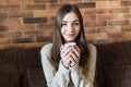 Beautiful young woman relaxing on the sofa at home, watching tv and enjoying coffee Royalty Free Stock Photo