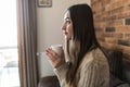 Beautiful young woman relaxing on the sofa at home, watching tv and enjoying coffee Royalty Free Stock Photo