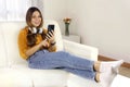 Beautiful young woman relaxing on sofa using smartphone Royalty Free Stock Photo