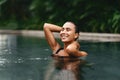 Beautiful young woman relaxing in spa swimming pool.