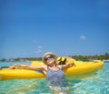 The most relaxing holiday. A beautiful young woman relaxing in a tropical ocean with her boat. Royalty Free Stock Photo