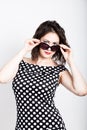 Beautiful young woman removes sun glasses, wears a dress with polka dots Royalty Free Stock Photo