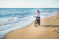 Beautiful young woman rides a Bicycle along the sea on a sandy beach.