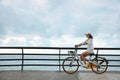Beautiful young woman riding bicycle along embankment. Space for text Royalty Free Stock Photo