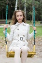 Beautiful young woman is riding in the park on a swing