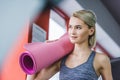 beautiful young woman with rolled yoga mat Royalty Free Stock Photo