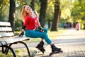 Beautiful young woman in roller skates sitting on park bench Royalty Free Stock Photo