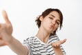 Beautiful young woman, romantic girl sending kisses at camera, taking selfie, standing in tshirt over white background Royalty Free Stock Photo