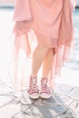 Beautiful young woman in rose dress and sport sneakers standing on the background of Venice canal and buildings. Italy, Europe. Royalty Free Stock Photo