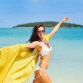 Beautiful young woman running on the beach with a yellow tissue