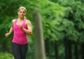 Beautiful young woman running in the park in sportswear