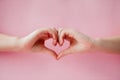 Beautiful young woman`s hand with perfect manicure making heart on pink background. Flat lay style Royalty Free Stock Photo