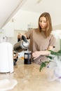 Beautiful young woman sanding at kitchen counter, pouring herself a cup of hot coffee, enjoying leisure time at home in Royalty Free Stock Photo