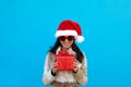 Woman in santa hat and sunglasses with gift blue background Royalty Free Stock Photo