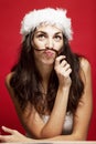 Beautiful young woman in santa claus hat smiling. Christmas tale. Postcard.  Red background Royalty Free Stock Photo