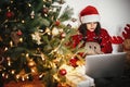 Beautiful young woman in santa hat sitting with laptop at golden Royalty Free Stock Photo