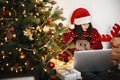 Beautiful young woman in santa hat sitting with laptop at golden Royalty Free Stock Photo