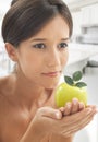 Beautiful young woman with satin hair and black eyes holding an apple in her hands Royalty Free Stock Photo