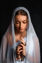 Beautiful young woman with a scarf on her head, and a rosary in her hands, humble look, believing woman