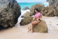 Beautiful young woman with body in swimwear posing on beach with big stones Royalty Free Stock Photo