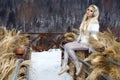 Beautiful young woman in mini dress, standing on the snow and view of the mountains.