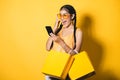 Beautiful young woman with shopping bags using her smart phone Royalty Free Stock Photo