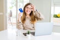 Beautiful young woman shopping online using laptop and credit card with happy face smiling doing ok sign with hand on eye looking Royalty Free Stock Photo