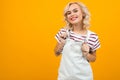 Beautiful young woman with short blonde curly hair and bright makeup in white overalls gesticulated and smiles, portrait