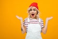 Beautiful young woman with short blonde curly hair and bright makeup in white overalls and red hat gesticulated and