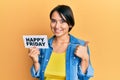 Beautiful young woman with short hair holding happy friday message paper smiling happy and positive, thumb up doing excellent and Royalty Free Stock Photo